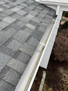 A cleared gutter beside a shingle roof